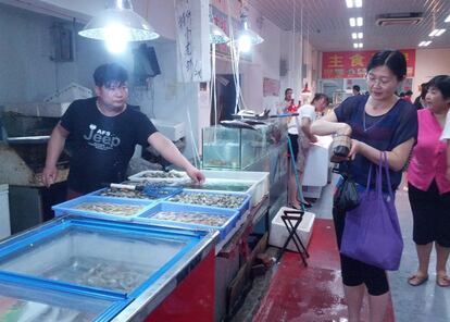 Pekín. Una mujer compra marisco en un mercado de barrio donde el género suele exhibirse vivo dentro de peceras.