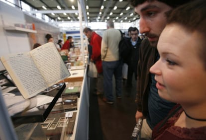 Una pareja observa un volumen manuscrito en la Feria de Durango.