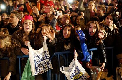Unas chicas sujetan sus bolsas para llenarlas de caramelos al paso de las carrozas en Madrid.