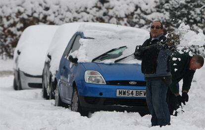 Un hombre quita la nieve de un coche en Manchester.