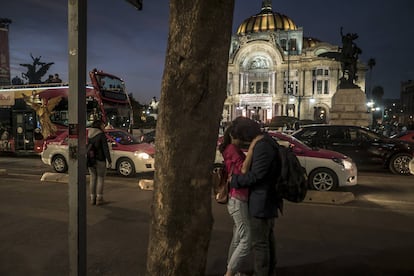 Una pareja se besa frente al Palacio de Bellas Artes en el centro histórico.