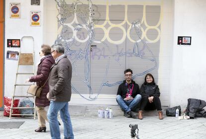 La maestra Nines Moro (sentada) realizó una encuesta con sus amigos para elegir la obra que decoraría su garaje en la calle del Cid. <i>Primavera 2019',</i> del artista palentino Daniel Revuelta, alias <i>Fumantwo,</i> ganó. La asociación ZOES, que cuenta con una decena de colaboradores que trabajan de manera permanente en ella, muestra varios bocetos a los vecinos para que elijan la obra que quieren que decore su cochera. Revuelta, que ha trabajado como ilustrador en el Festival Internacional de Cortometrajes de Aguilar de Campoo, su ciudad natal, se enteró del concurso del Barrio del Oeste por un familiar que vive en Salamanca.