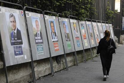 Una mujer pasa delante de los carteles de los candidatos de las elecciones presidenciales francesas en París.