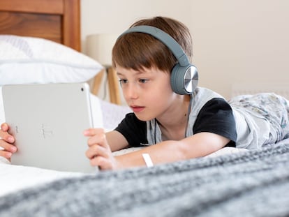 Un niño usa una tablet en su dormitorio.