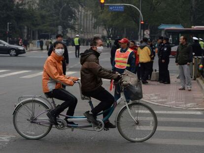 Una pareja china pasa ante el hotel de Pek&iacute;n se re&uacute;nen los l&iacute;deres.