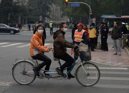 Una pareja china pasa ante el hotel de Pek&iacute;n se re&uacute;nen los l&iacute;deres.