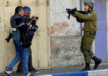 Un soldado israelí apunta con su arma junto a dos reporteros, el pasado diciembre en Hebrón (Cisjordania).