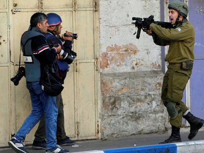 Un soldado israelí apunta con su arma junto a dos reporteros, el pasado diciembre en Hebrón (Cisjordania).