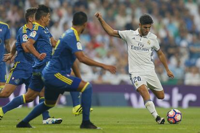 Marco Asensio (d) del Real Madrid golpea la pelota ante la presión de los defensas del Celta de Vigo.