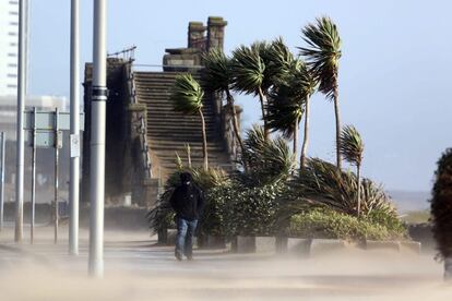 Un hombre camina bajo una tormenta de arena en una calle de Swansea, en el sur de Gales (Reino Unido). El temporal ha provocado las peores inundaciones en décadas, cortes de electricidad y problemas en el tráfico, mientras nuevas precipitaciones amenazan con empeorar la situación. 