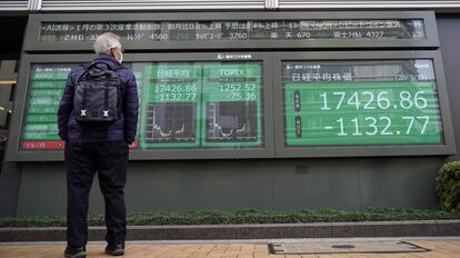 Un hombre mira un panel con los datos de la bolsa de Japón.