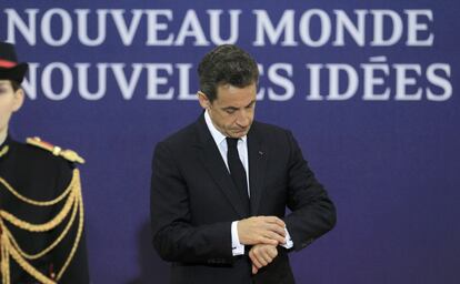 Sarkozy consulta su reloj mientras espera la llegada de mandatarios a la cumbre del G-20.