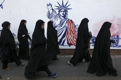 Un grupo de mujeres pasa cerca de un mural que representa la Estatua de la Libertad sin el brazo que sujeta la antorcha, al volver del funeral del general Qasem Soleimani, en Teherán (Irán). 