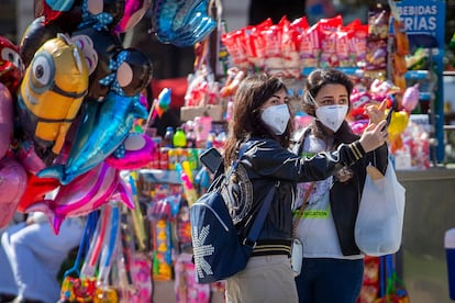 Dos turistas con mascarillas se hacen una foto en el centro de Barcelona.