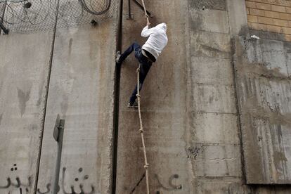 Un hombre utiliza una cuerda para saltar el muro de hormigón que separa Cisjordania de Jerusalén (Israel).