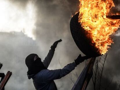 Un manifestante lanza un neum&aacute;tico ardiendo para montar una barricada en la plaza de la Independencia de Kiev. 