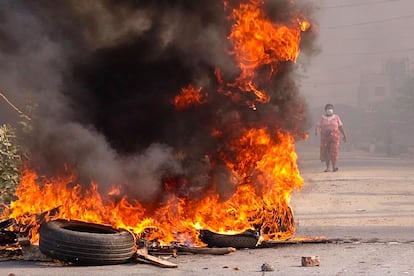 Una mujer camina cerca de barricadas en llamas durante la represión por parte de las fuerzas de seguridad contra los manifestantes que protestan contra el golpe militar en Mandalay (Myanmar).