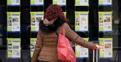 Una mujer examina los carteles de una agencia inmobiliaria en Madrid.