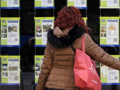 Una mujer examina los carteles de una agencia inmobiliaria en Madrid.