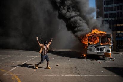 Un estudiante gesticula al lado de un autobús en llamas tras una protesta contra las tasas universitarias, en Johannesburgo (Sudáfrica).