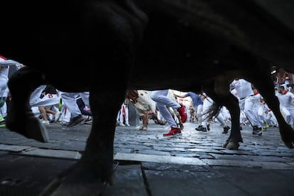 Detail of one of the bulls from the Cebada Gago ranch, with the runners in the background, during the second running of the bulls.