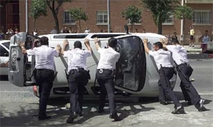 Varios policías enderezan un coche volcado durante los disturbios en Sevilla la semana pasada.