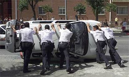 Varios policías enderezan un coche volcado durante los disturbios en Sevilla la semana pasada.