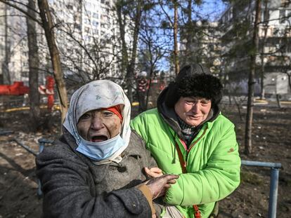 A woman is evacuated from a burning apartment building in Kyiv on March 15, 2022, after strikes on residential areas killed at least two people, Ukraine emergency services said as Russian troops intensified their attacks on the Ukrainian capital. - A series of powerful explosions rocked residential districts of Kyiv early today killing two people, just hours before talks between Ukraine and Russia were set to resume. (Photo by Aris Messinis / AFP)