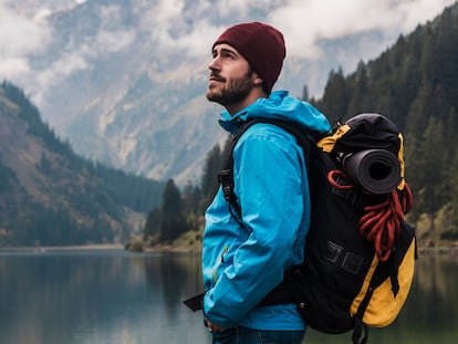 Hombre haciendo senderismo en invierno y mirando el paisaje.