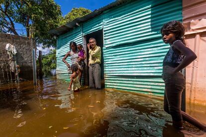 El agua ha arrasado con casas, cultivos y preocupa que se pueda generar una emergencia sanitaria. Una familia a la puerta de su casa en San Félix, en el Estado de Bolívar, el pasado 10 de agosto.