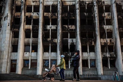 Una familia pasa ante el edificio quemado del Ayuntamiento de la ciudad kazaja de Almaty, en la plaza de la República.