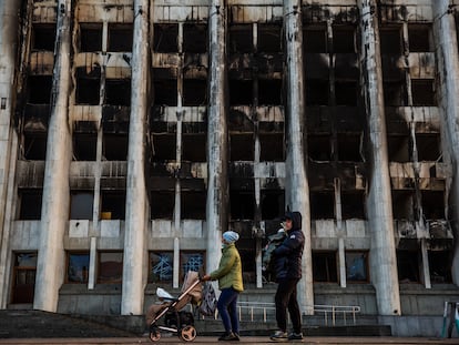 Una familia pasa ante el edificio quemado del Ayuntamiento de la ciudad kazaja de Almaty, en la plaza de la República.