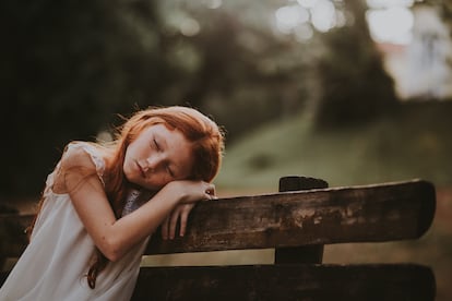 Una niña se duerme en un banco.