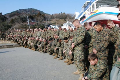Marines de EE UU guardan un minuto de silencio antes de comenzar la búsqueda de cadáveres en la aldea de Kesennumaoshima.