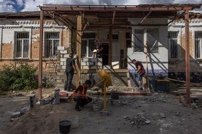 Varios voluntarios reparan una escuela de primaria destruida por los ataques rusos en Hostomel, al noroeste de Kiev, este 18 de julio. 