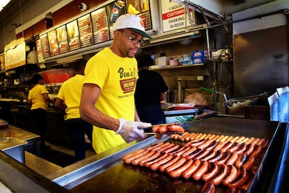 Calvin Roberts uno de los empleados da la vuelta a las salchichas ahumadas en la plancha que tiene vista a la calle U Street. Es habitual que los curiosos se asomen al ventanal mientras los camareros trabajan a un ritmo frenético.