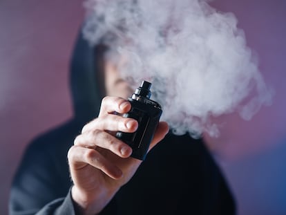 Un joven fuma con un cigarrillo electrónico.