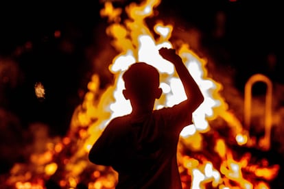 Un niño frente a una hoguera en una playa de Barcelona durante la verbena de Sant Joan, en 2022.