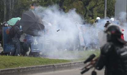 Un grupo de estudiantes se protegen del gas lacrimógeno lanzado por la policía durante las protestas en Bogotá (Colombia).