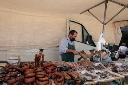 José Francisco Pérez, de 42 años, cortando jamón en su puesto de charcutería en el mercadillo de Cedillo.