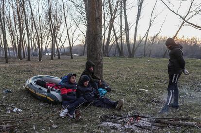 Un grupo de migrantes descansa con su bote mientras esperan para poder cruzar el río Evros en Turquía, el 1 de marzo. "No nos dejan regresar. Vienen con autobuses privados y nos llevan desde este paso a otro. Y desde allí a otro. Y luego nos traen de vuelta. Juegan con nosotros, nada más", asegura Nasser Abu Sami, otro sirio, que lleva dos días con su familia en la zona.