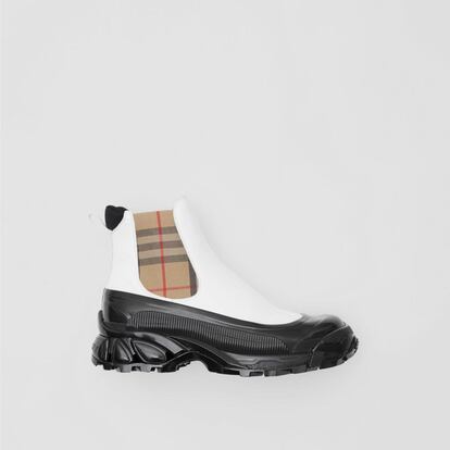 Unas botas de estilo british. Uno de los últimos lanzamientos de Burberry son estas botas Chelsea en vinilo con paneles a cuadros vintage checks. Disponen de una cubierta brillante inspirada en las botas de agua de color blanco y beis, y la suela prominente presenta motivos cruzados en color negro, en referencia a los icónicos cuadros de la casa británica. Están fabricadas en Italia, utilizando mayoritariamente piel de ovino, piel de vacuno, algodón, poliéster y goma. El modelo está diseñado sin cordones y con tiradores en el talón para ajustarlo cómodamente al pie. También en el talón está grabado el logotipo de Burberry. Precio: 590 euros.