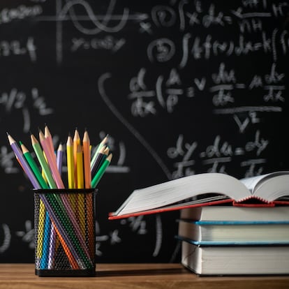 Back to school supplies. Books and blackboard on wooden background