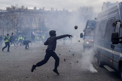 La Prefectura de la Policía de París ha anunciado más de 40 detenciones a mediodía y se han empleado cañones de agua y gases lacrimógenos contra los manifestantes en los emblemáticos Campos Elíseos. En la imagen, un manifestante lanza piedras a las furgonetas de la policía antidisturbios en París.