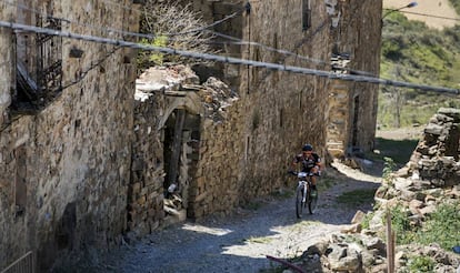 Un ciclista pasea entre casas abandonadas de Sarnago (Soria).  