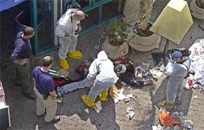 Policías israelíes examinan el cuerpo del joven palestino que se inmoló ayer junto a un restaurante en Netanya.