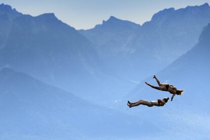 Dos mujeres saltan al lago de Ginebra, frente a los Alpes suizos y franceses, en el Festival Summerslide de Clarens (Suiza).