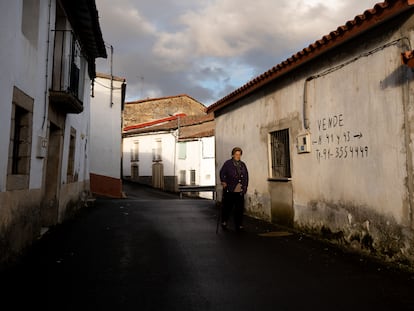 Una vecina de Alcañices (Zamora) pasa por delante de una vivienda en venta en la localidad.