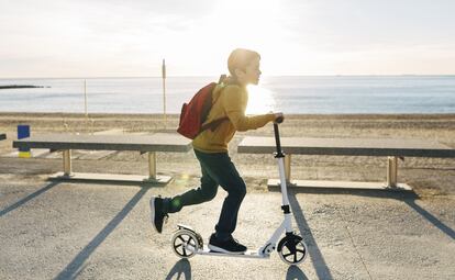 Un niño juega con un patinete eléctrico en la orilla de la playa.