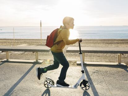 Un niño juega con un patinete eléctrico en la orilla de la playa.